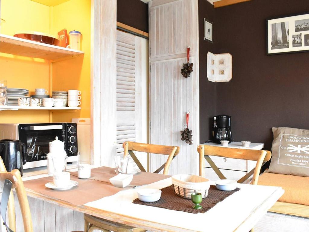 une cuisine avec une table et des chaises et une cuisine aux murs jaunes dans l'établissement Studio cosy au pied des pistes à Méribel – Balcon, TV, animaux acceptés, ski à 100 m ! - FR-1-180-30, à Les Allues