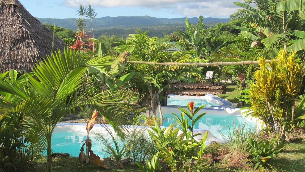 a view of a pool in a resort with palm trees at Les Cottages de Bellevue Ecolodge in Port Vila