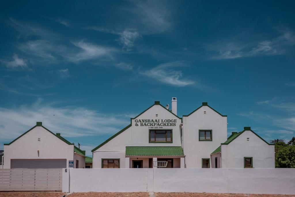a white building with a sign on top of it at Gansbaai Lodge & Backpackers in Gansbaai