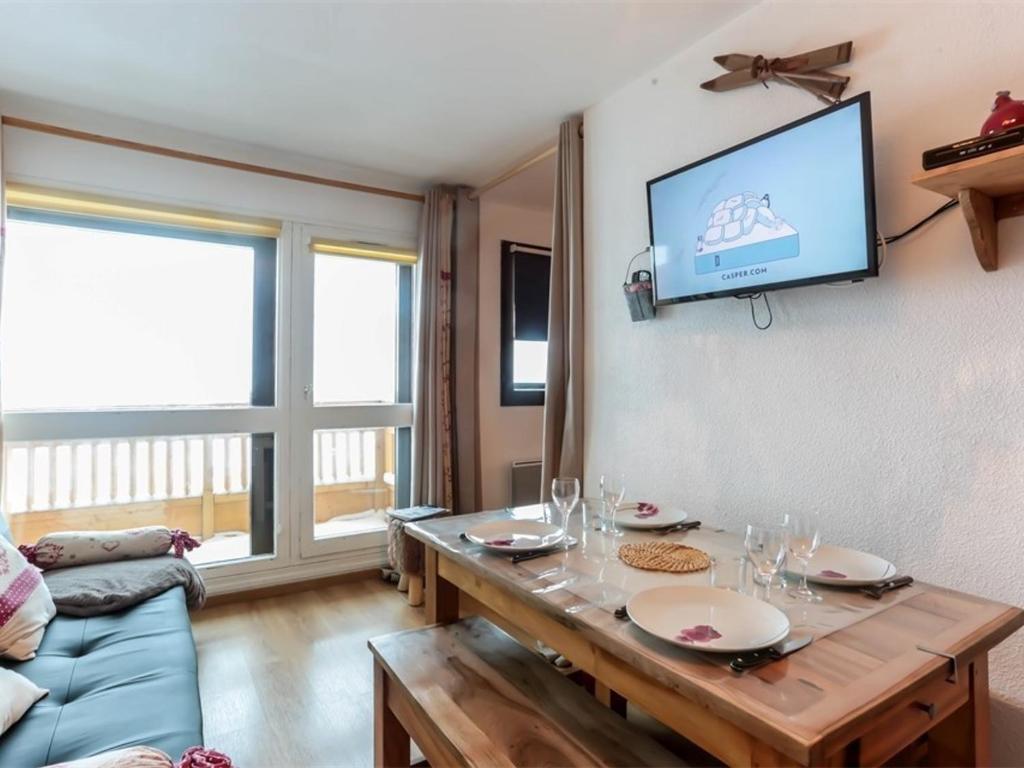 a living room with a table and a tv on the wall at Val Thorens - Appartement 4 pers, 2 pièces rénové, plein centre - FR-1-637-53 in Val Thorens