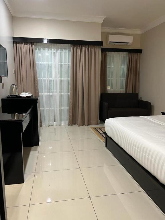a bedroom with a bed and a desk and a couch at Aneeda Inn in Pantai Cenang