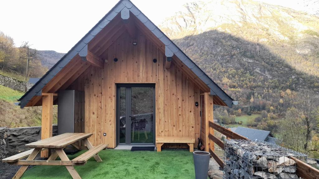 a wooden cabin with a picnic table in front of it at Chalet Sanset in Gèdre