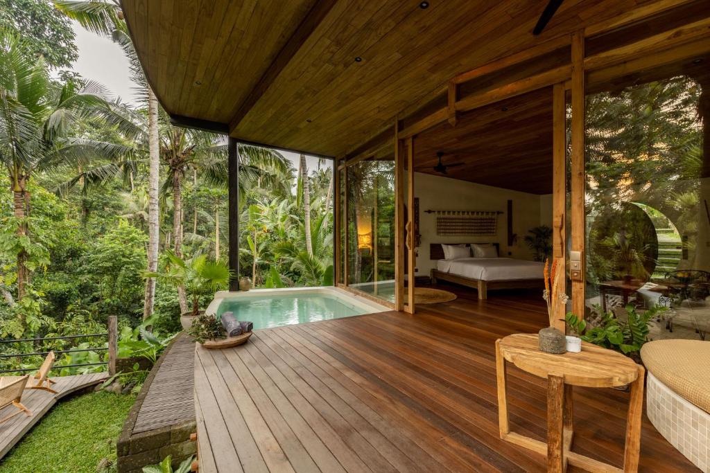 eine Holzterrasse mit einem Pool in einem Haus in der Unterkunft Casa Pohon Ubud in Ubud