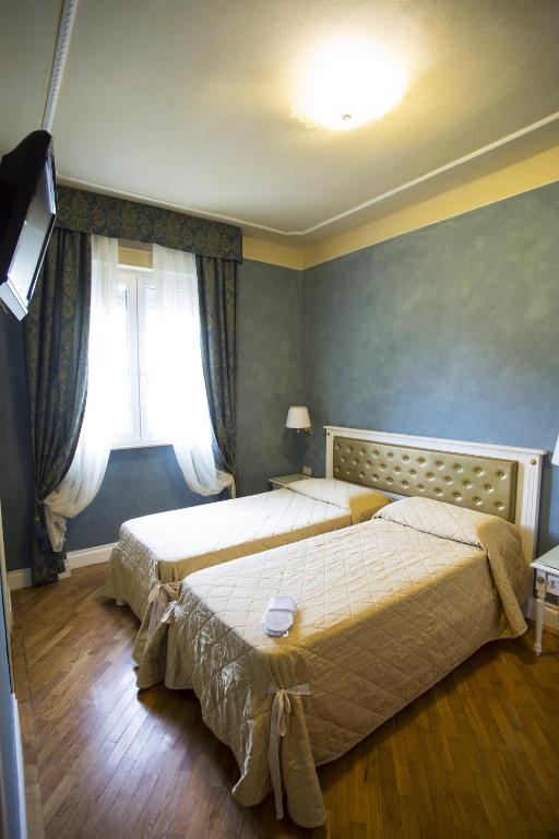 a bedroom with two beds and a window at Hotel Gennarino in Livorno