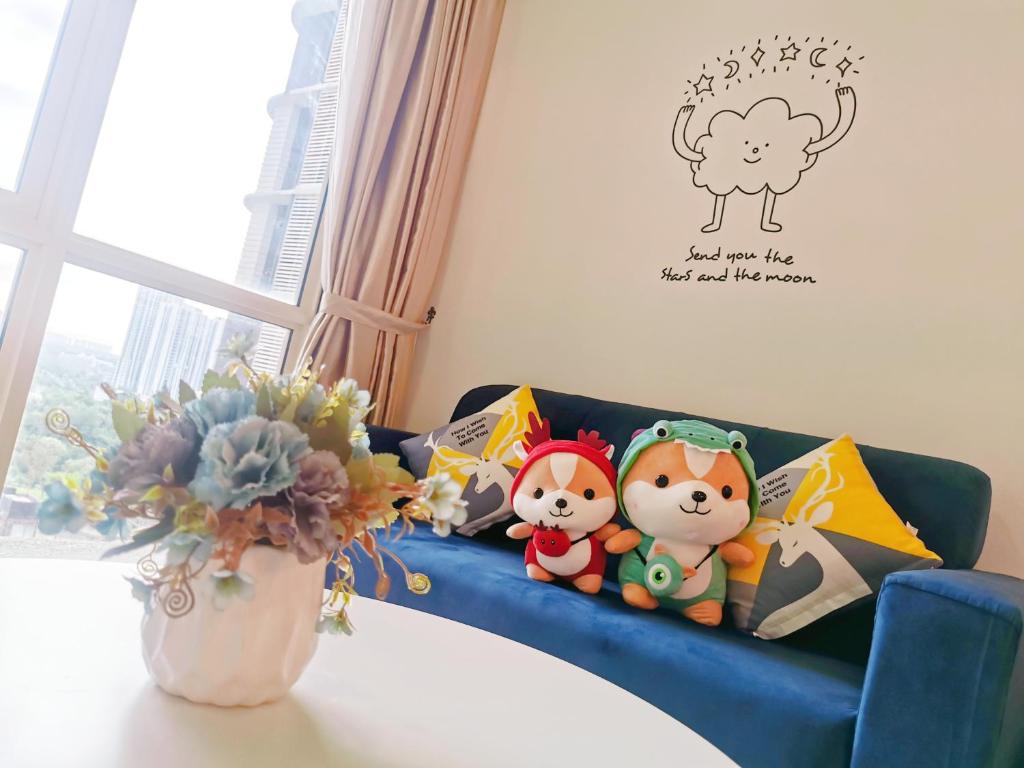 two stuffed animals sitting on a blue couch with a vase of flowers at Legoland-3min Walk-HappyDream Suite at Afiniti -8pax-Cozy,Comfy&Convenience 2BR with Bathub in Nusajaya