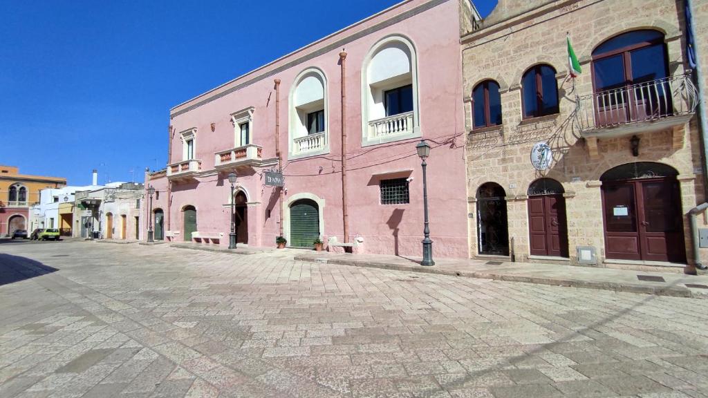 um grande edifício rosa numa rua de calçada em Foresteria di Casa Winspeare em Depressa