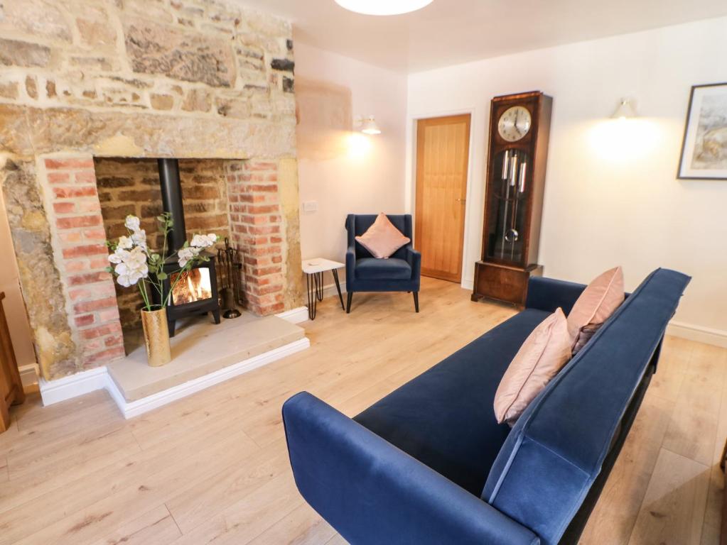 a living room with a blue couch and a fireplace at 3 Mill Wynd in Darlington