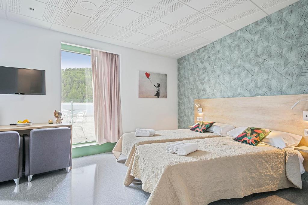 a hotel room with two beds and a television at Les Begues Apartments in Begues