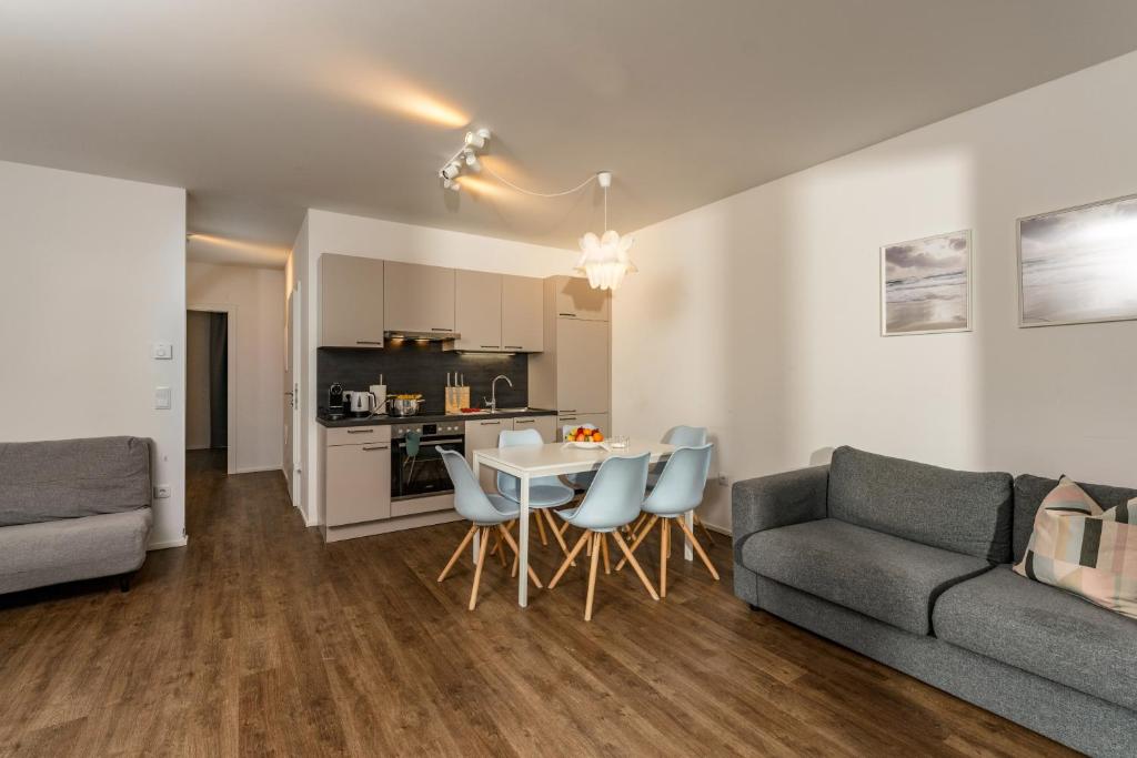 uma sala de estar com um sofá, uma mesa e cadeiras em APSTAY Serviced Apartments - Self Check-in em Graz