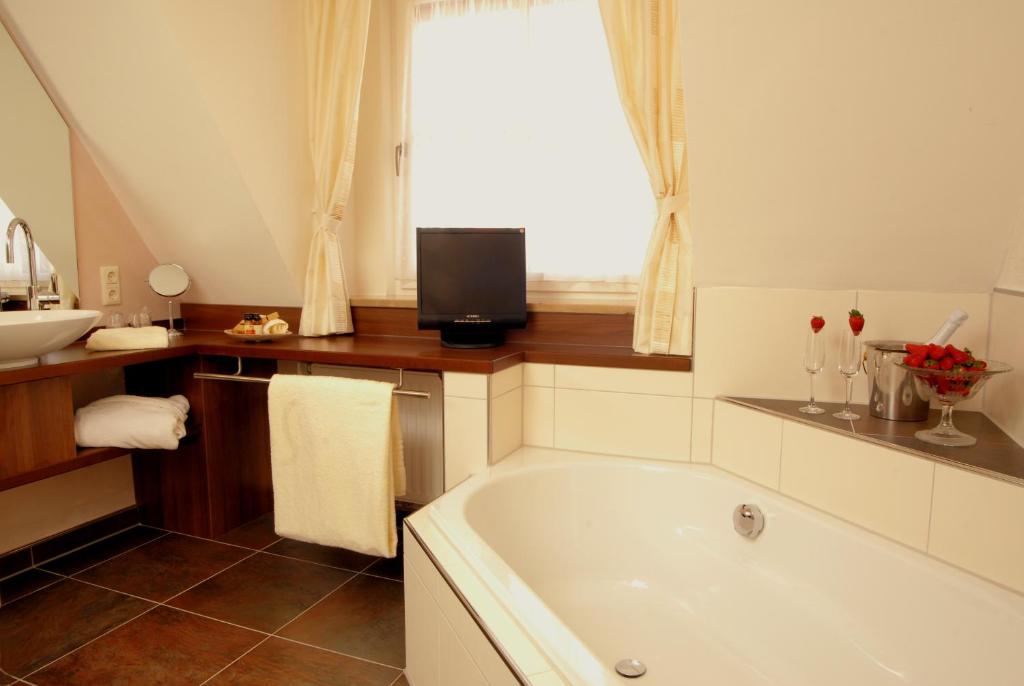 a bathroom with a tub and a sink and a window at Hotel Sonne in Füssen