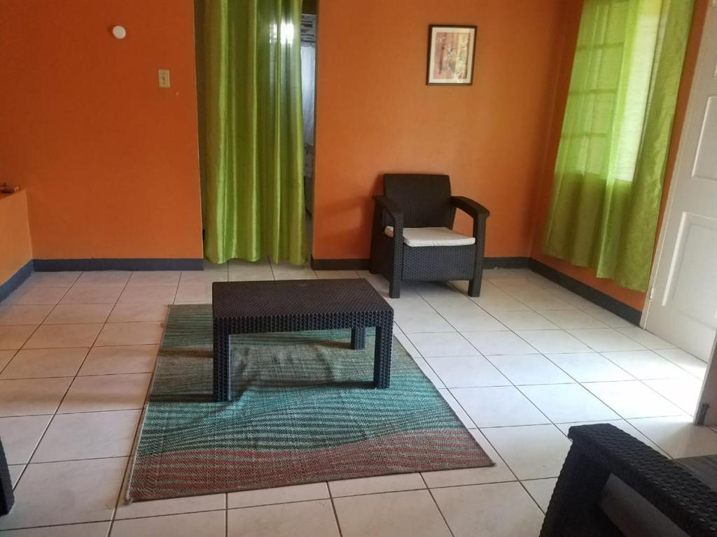 a living room with a chair and a table at Unity Villa 3 bedroom with fans Wifi Parking in Montego Bay