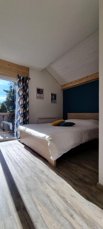 un grand lit dans une chambre avec une grande fenêtre dans l'établissement Mont Bivouac, chambre,entrée et Sdb privée,balcon vue MtBlanc, à Passy