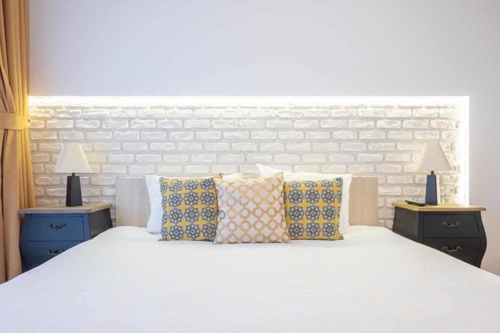 a bedroom with a white bed with pillows and two lamps at Brick Flats in Oradea