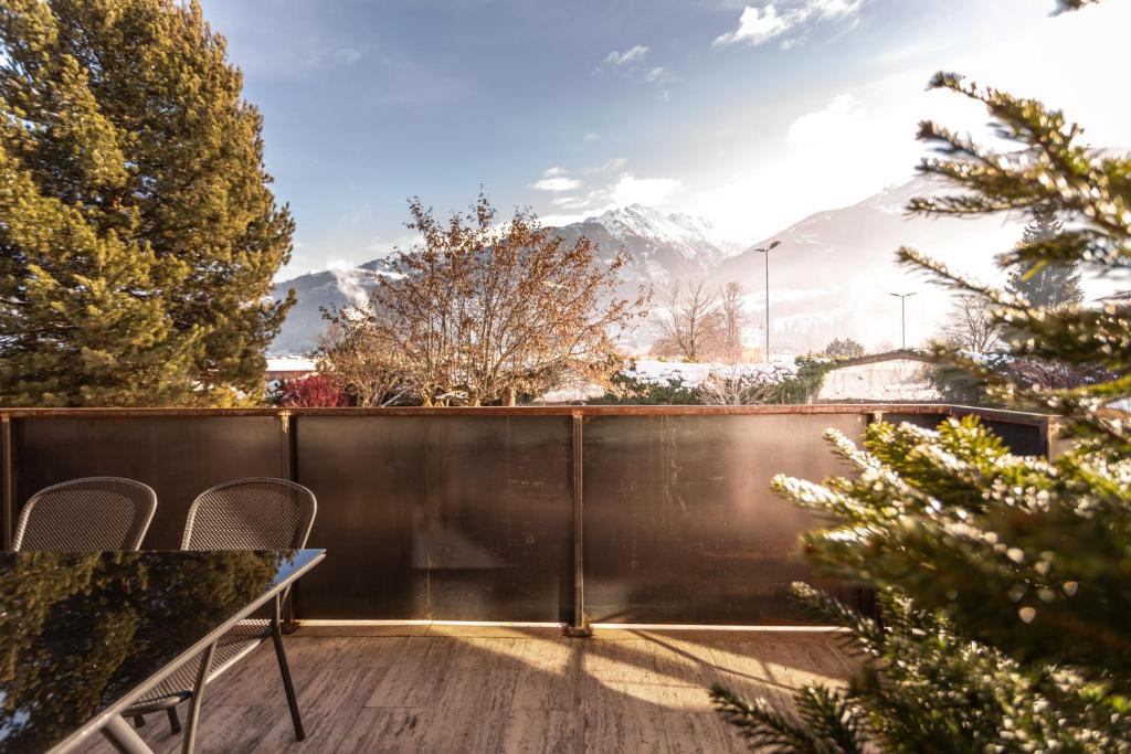 a balcony with a table and chairs and mountains at Alpine View Apartments in Niedernsill