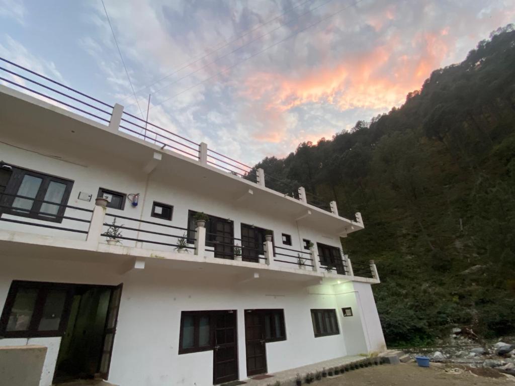 una vista de una casa con una puesta de sol en el fondo en Chirag Homestay Kainchi, en Nainital