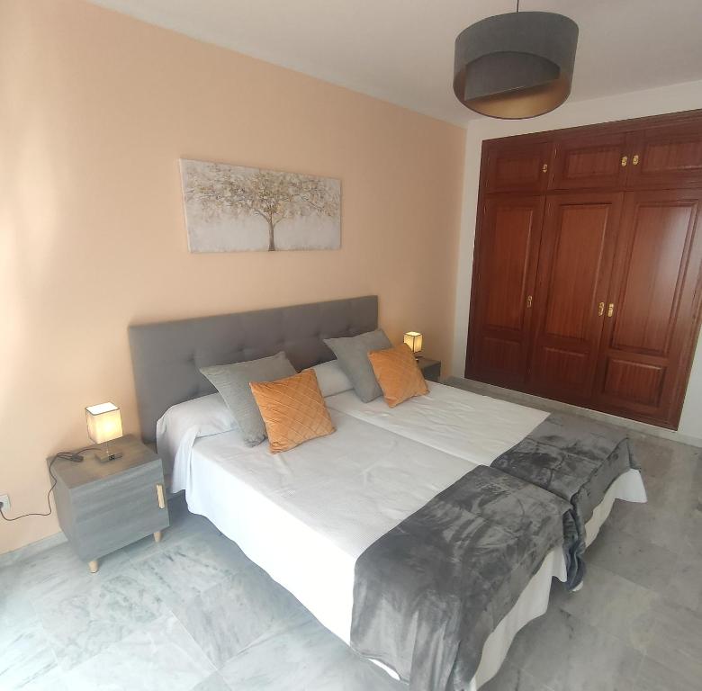 1 dormitorio con 1 cama blanca grande con almohadas de color naranja en Sanpedro Apartamentos Marbella, en Marbella