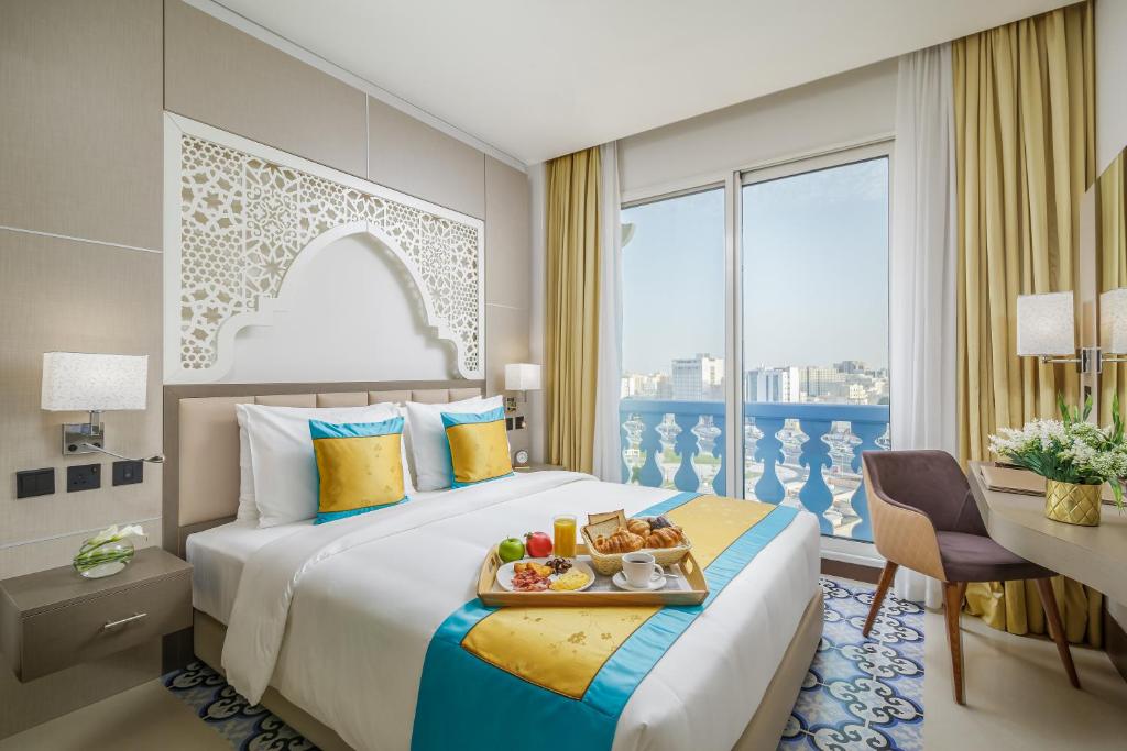 Una habitación de hotel con una cama con una bandeja de comida. en Central Inn Souq Waqif en Doha