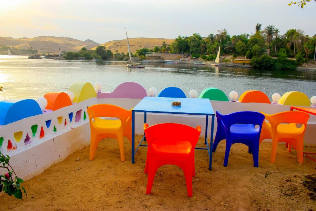 een tafel met kleurrijke stoelen naast het water bij Hamo Guest House in Aswan