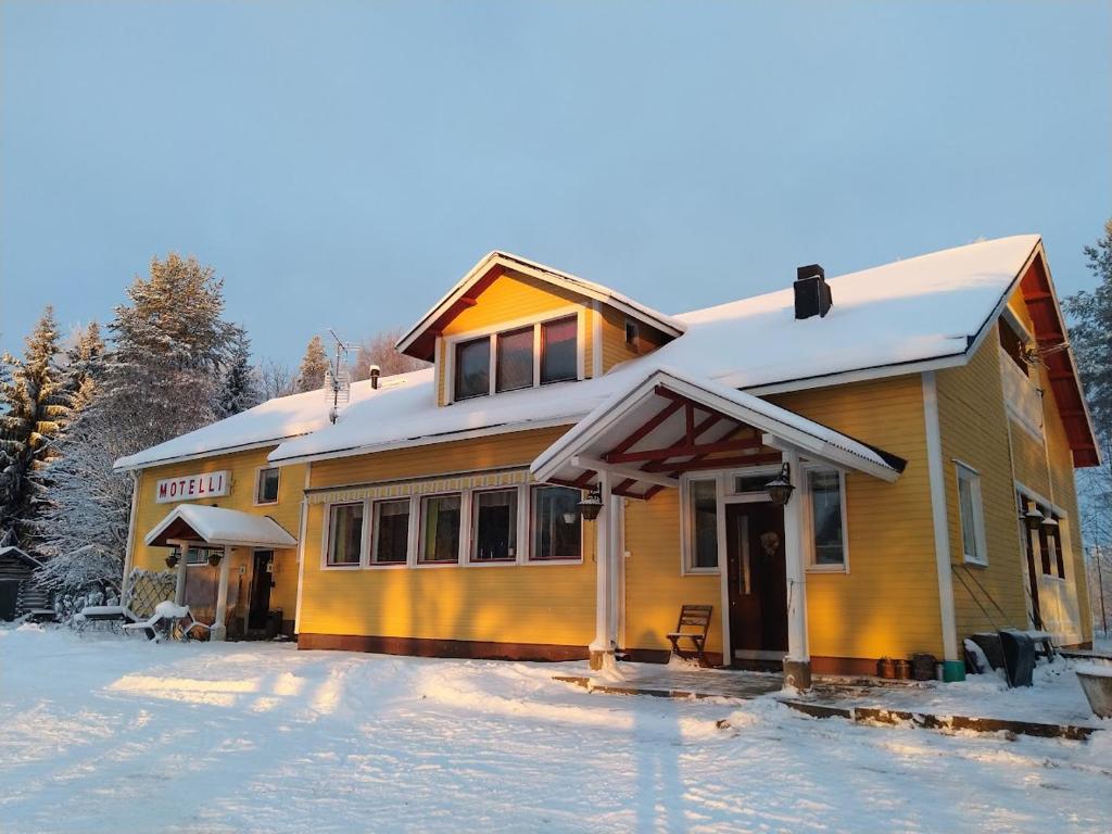 una casa amarilla con nieve en el suelo en Motelli Nuttulinna, en Nuttupera