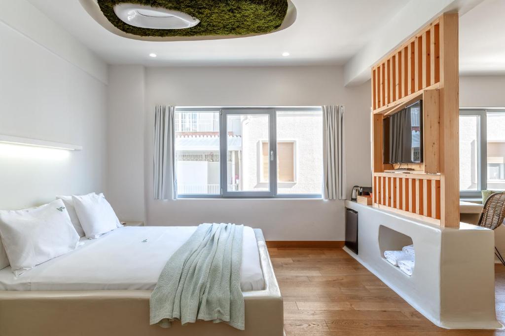 a white bedroom with a bed and a tv at LOFUS Bio-Suites in Athens