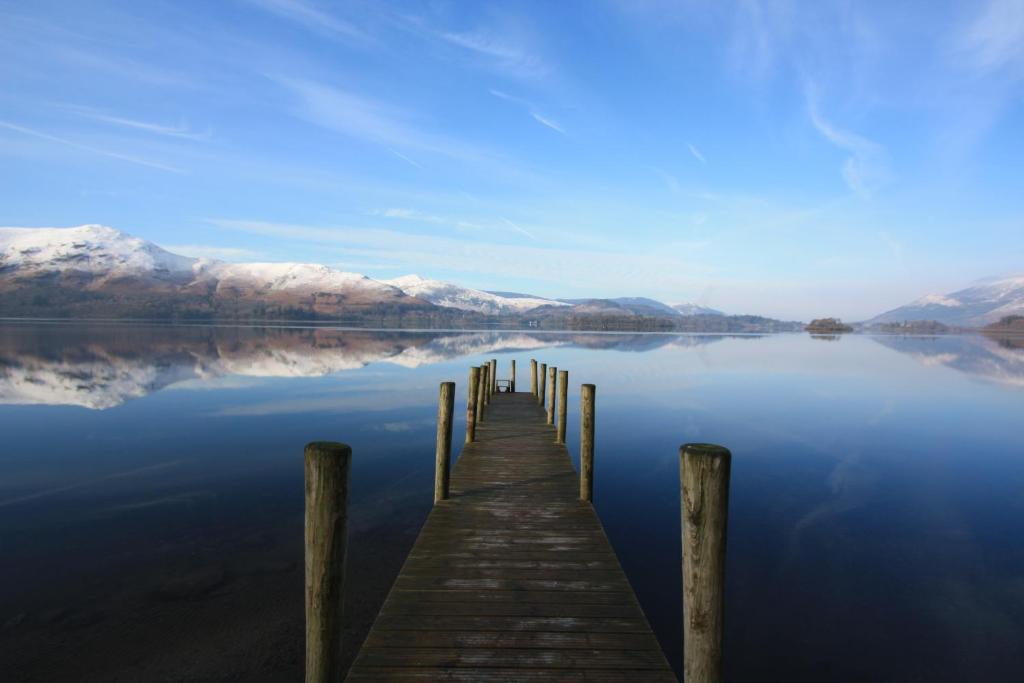 a dock on a lake with snow covered mountains at The Mary Mount Hotel in Keswick