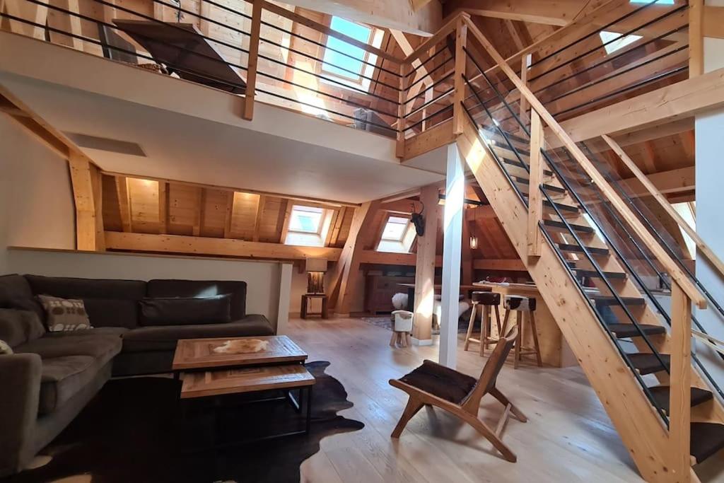 a living room with a couch and a staircase at Les Suites du Monetier, alliant le charme et l'authenticité d'un chalet de prestige au cœur du village in Le Monêtier-les-Bains