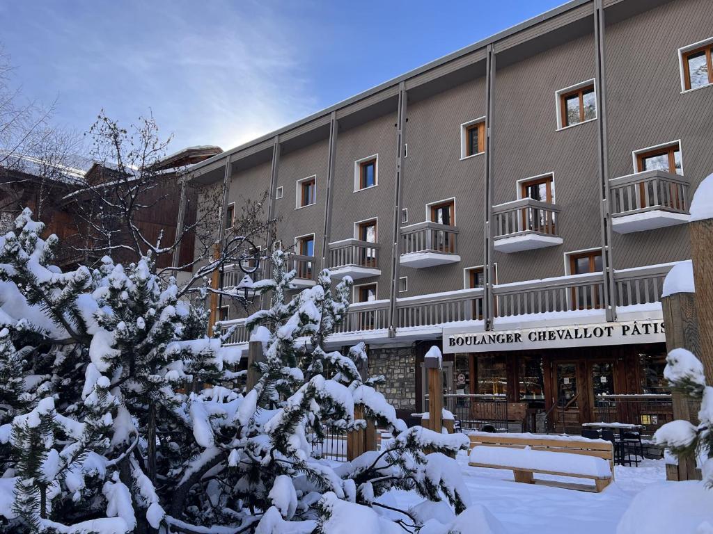 a building with snow covered trees in front of it at Everest Hotel in Val dʼIsère