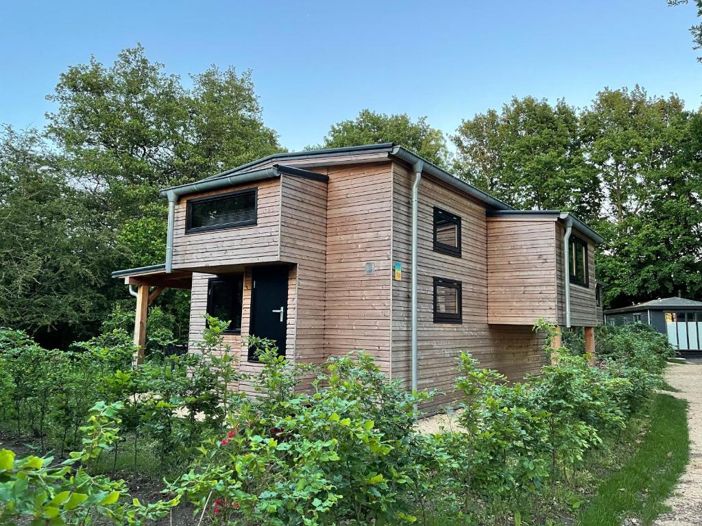 uma pequena casa de madeira situada num jardim em Tiny House am Veluwemeer im Europarcs Bad Hoophuizen em Hulshorst