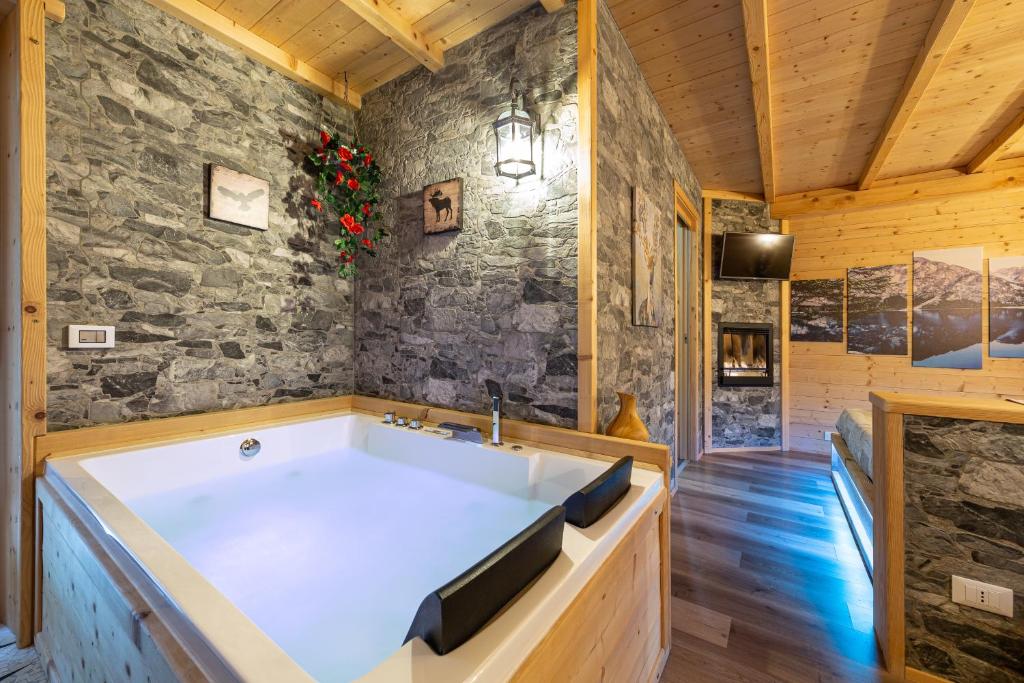 een badkamer met een groot bad in een stenen muur bij AL RANCH WELLNESS CADORE DOLOMITI APARTMENTS vicino Cortina e Misurina Tre Cime Lavaredo in Pieve di Cadore