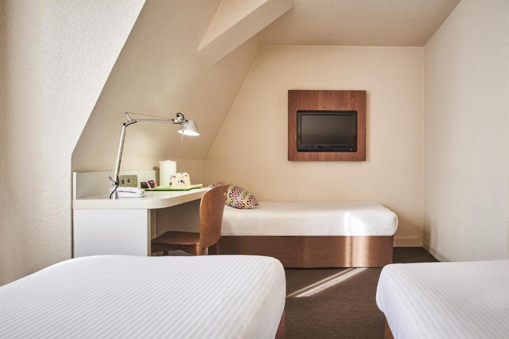 a room with two beds and a desk and a tv at Campanile Lyon Centre - Berges du Rhône in Lyon