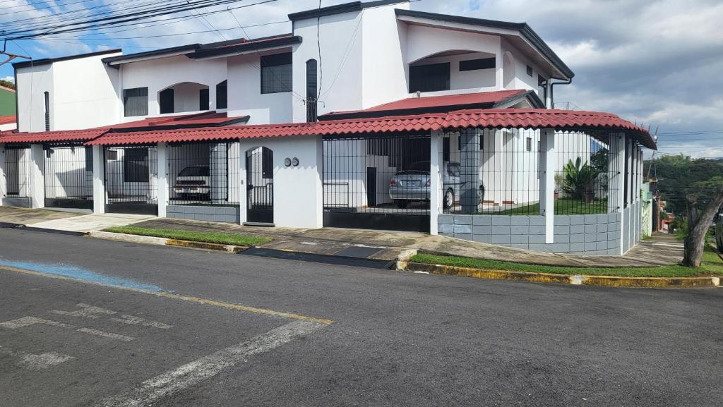 una casa blanca con una puerta a un lado de la carretera en Don Carlos Place, en Alajuela