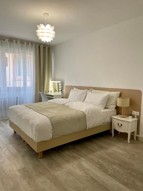 une chambre avec un grand lit et un lustre dans l'établissement Cozy Appartement Halles Strasbourg, à Strasbourg