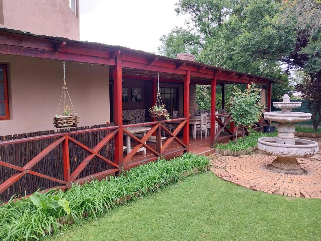 un porche cubierto de una casa con una fuente en Lily Guesthouse, en Bloemfontein