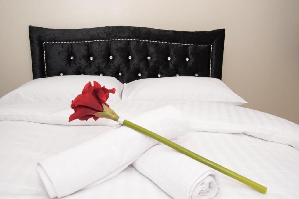 a red flower on a white bed with towels at The Kyoto House - Four Spacious Cosy Bedrooms I Contractor Friendly I Long Stay Offer I 5th Room available on request only in Derby