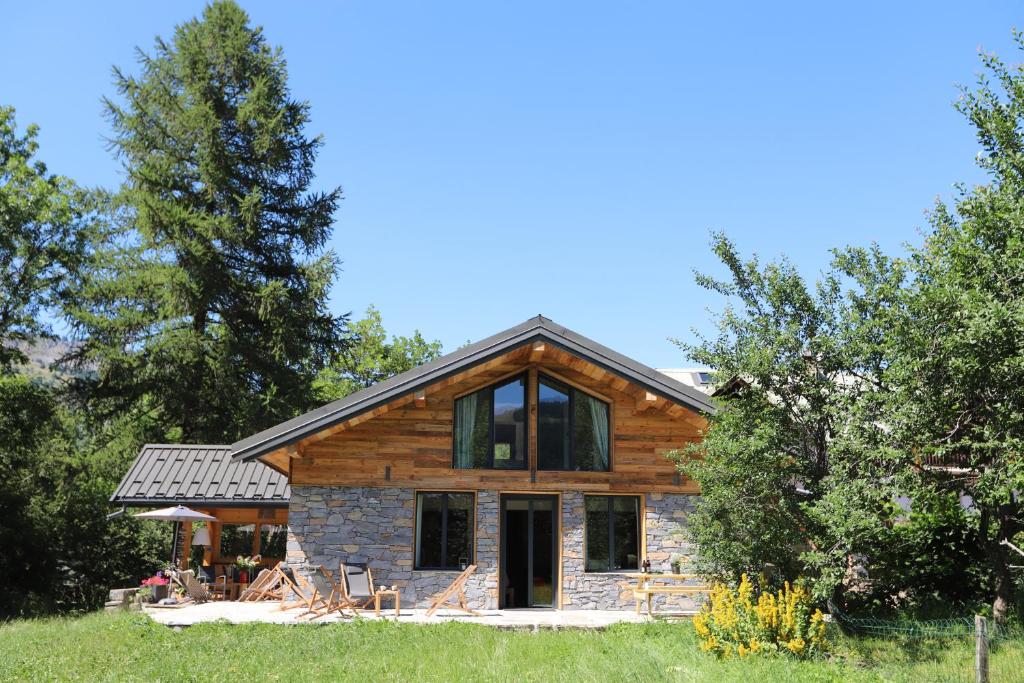 una casa de madera con porche y árboles en Chalet de l’Alpette, en Valloire