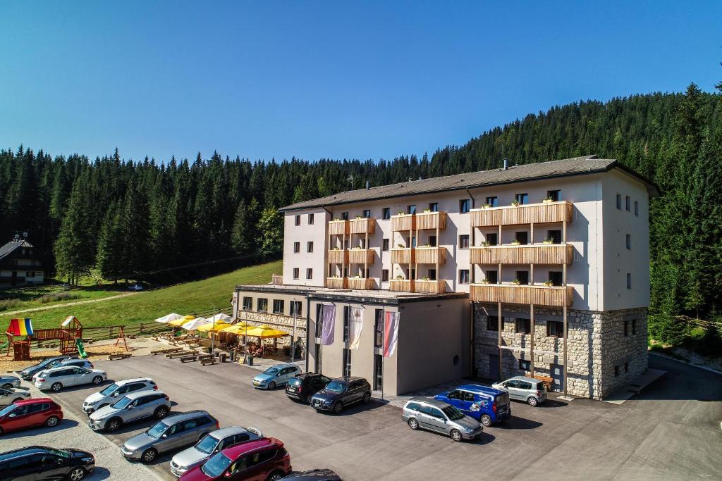 um parque de estacionamento com carros estacionados em frente a um edifício em Hotel Pokljuka em Goreljek