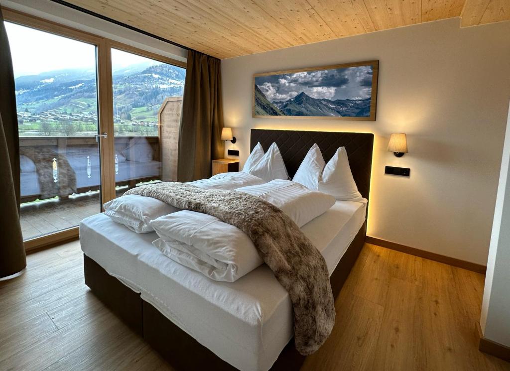 a bedroom with a large bed with a large window at Dorferwirt in Bramberg am Wildkogel