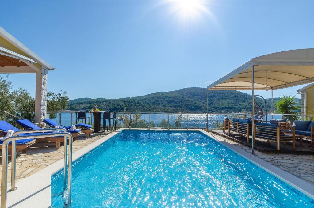 a swimming pool with chairs and a view of the water at Villa Paradise in Vela Luka