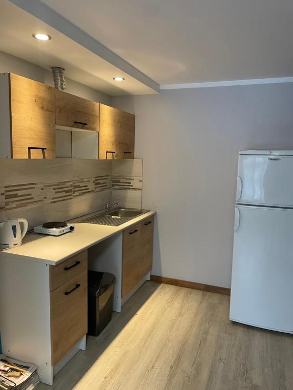 een keuken met een witte koelkast en houten kasten bij KurBrauksim Goldingen Apartments in Kuldīga