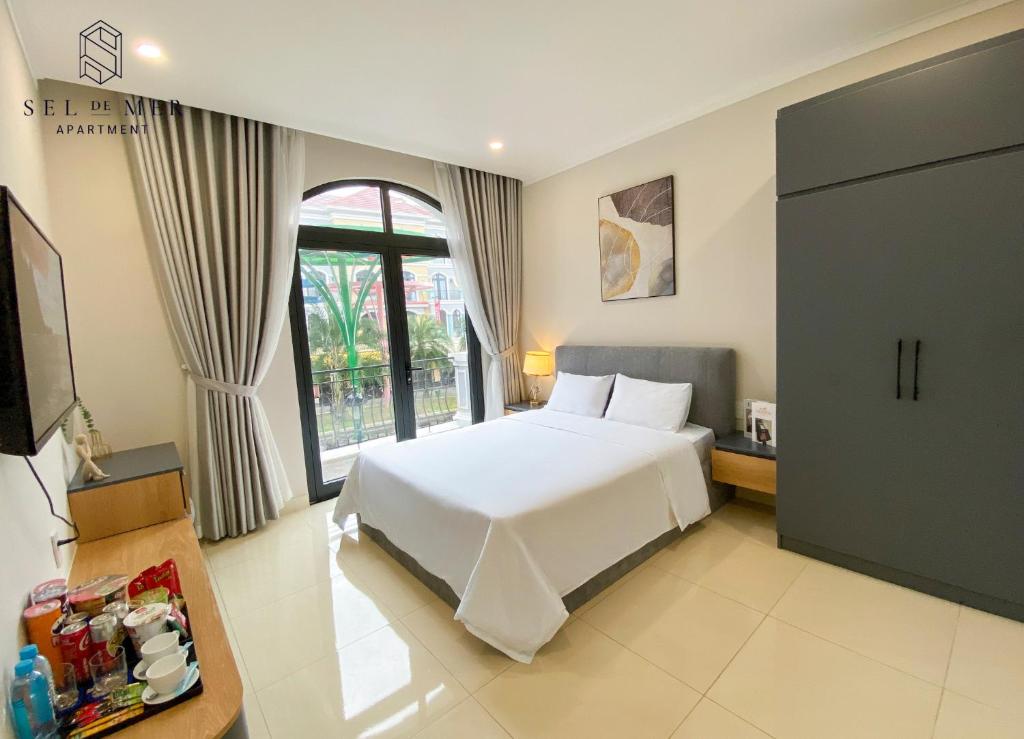 una camera con un letto bianco e una finestra di Sel de Mer Apartment Grand World Phu Quoc a Phu Quoc