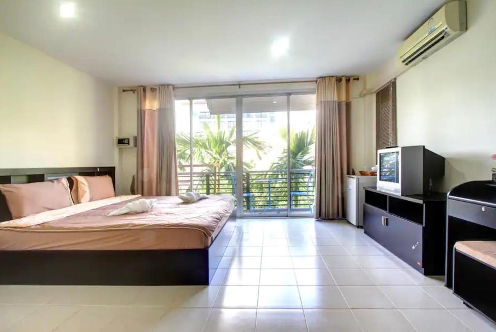a bedroom with a large bed and a large window at Kata Beach Guesthouse in Kata Beach