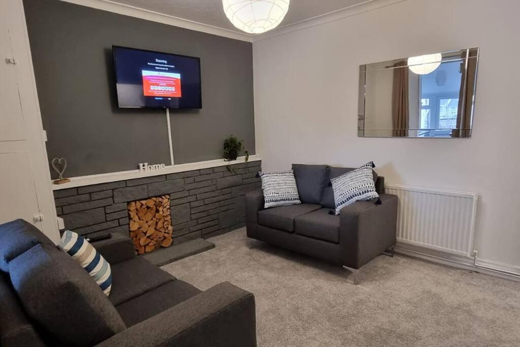 a living room with a couch and a tv on a wall at Bright and Modern 4 bed house- TV IN EVERY ROOM in Port Talbot