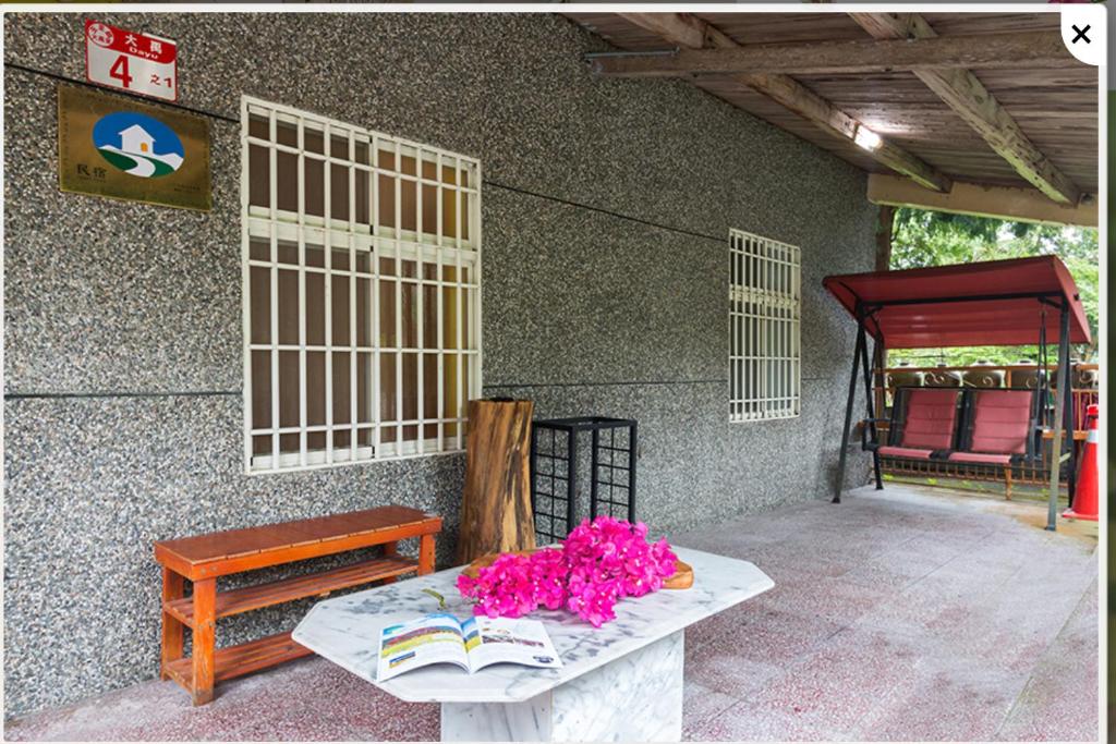 a table with pink flowers on it next to a building at Jia Jia Homestay in Yuli