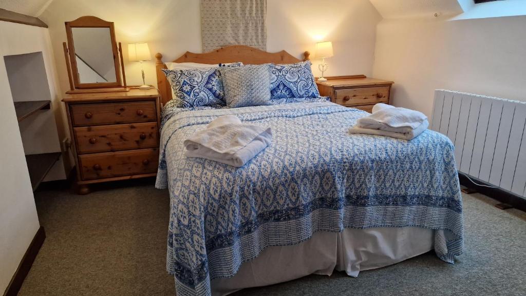 a bedroom with a bed with a blue and white comforter at Hayloft Cottage - Dog Friendly With Private Garden in Sidmouth