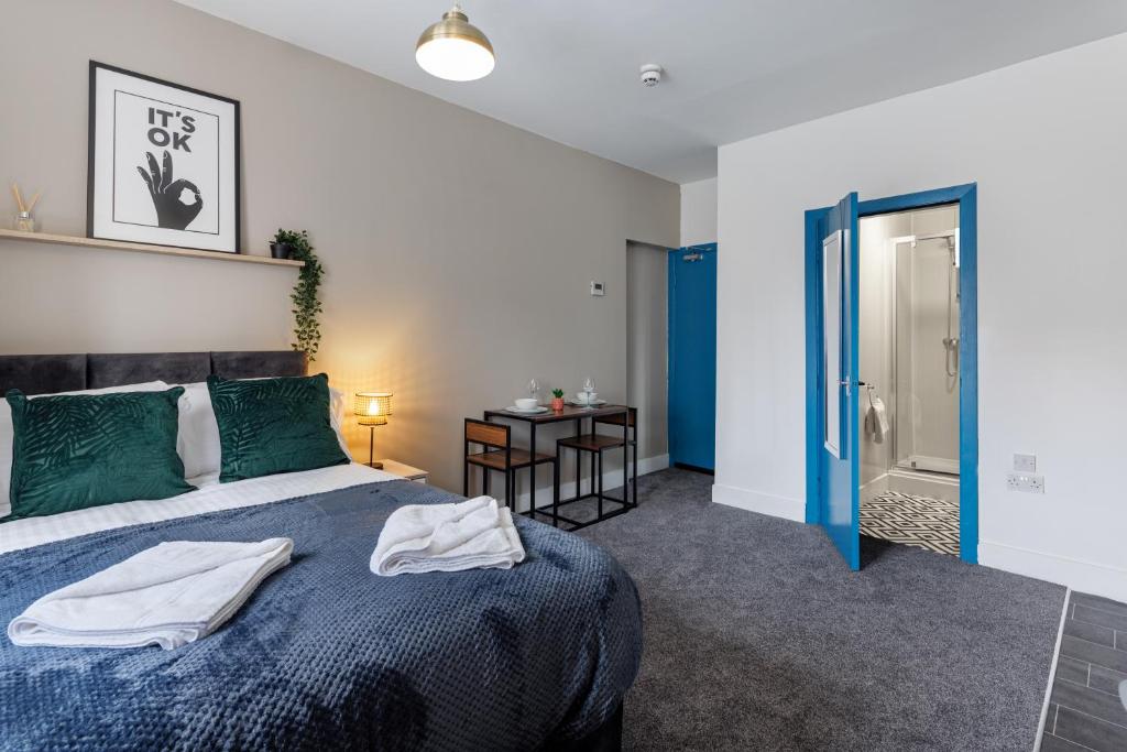 a bedroom with a blue and white bed and a bathroom at City Centre Studio 1 with Kitchenette, Free Wifi and Smart TV with Netflix by Yoko Property in Middlesbrough