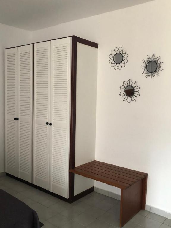 a bedroom with white cabinets and a bench on a wall at Village Kawann - Toumalacai 246 in Grand-Bourg