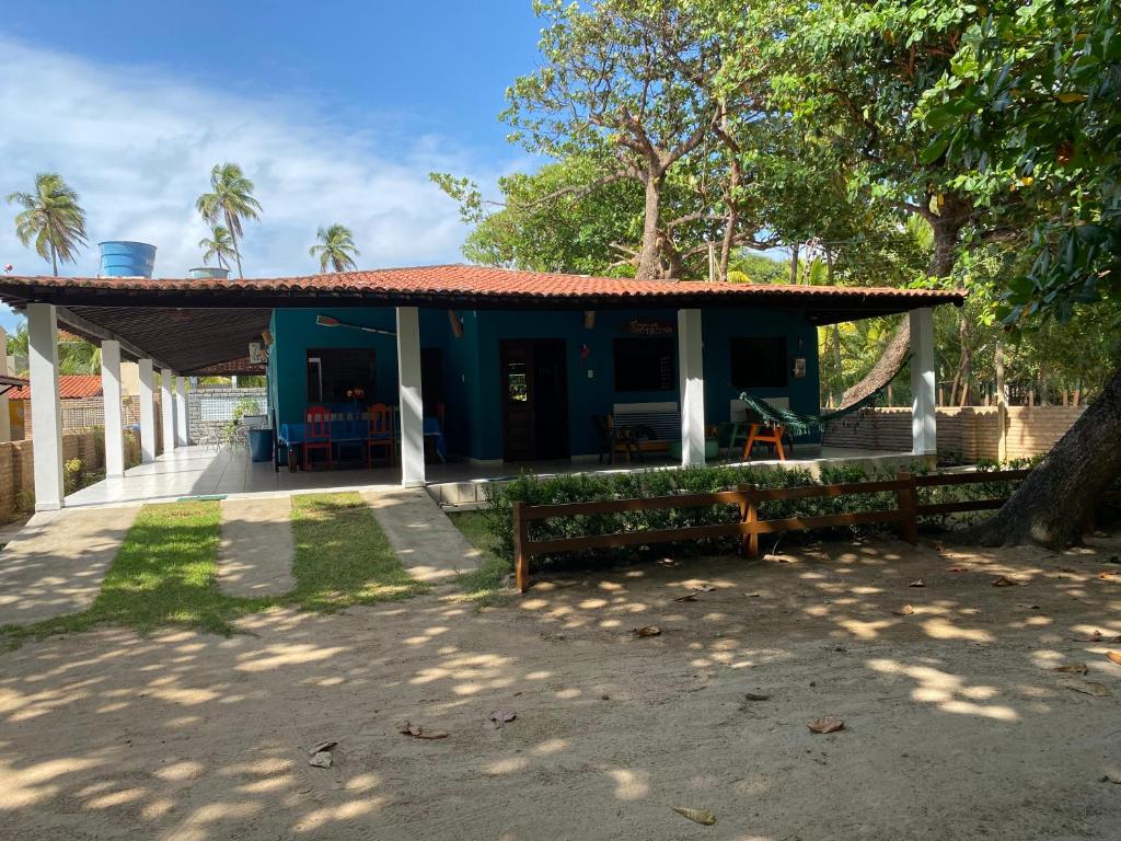 a blue house with a porch and a tree at Japaraiso I Casa Azul - Próxima ao Mar in Japaratinga