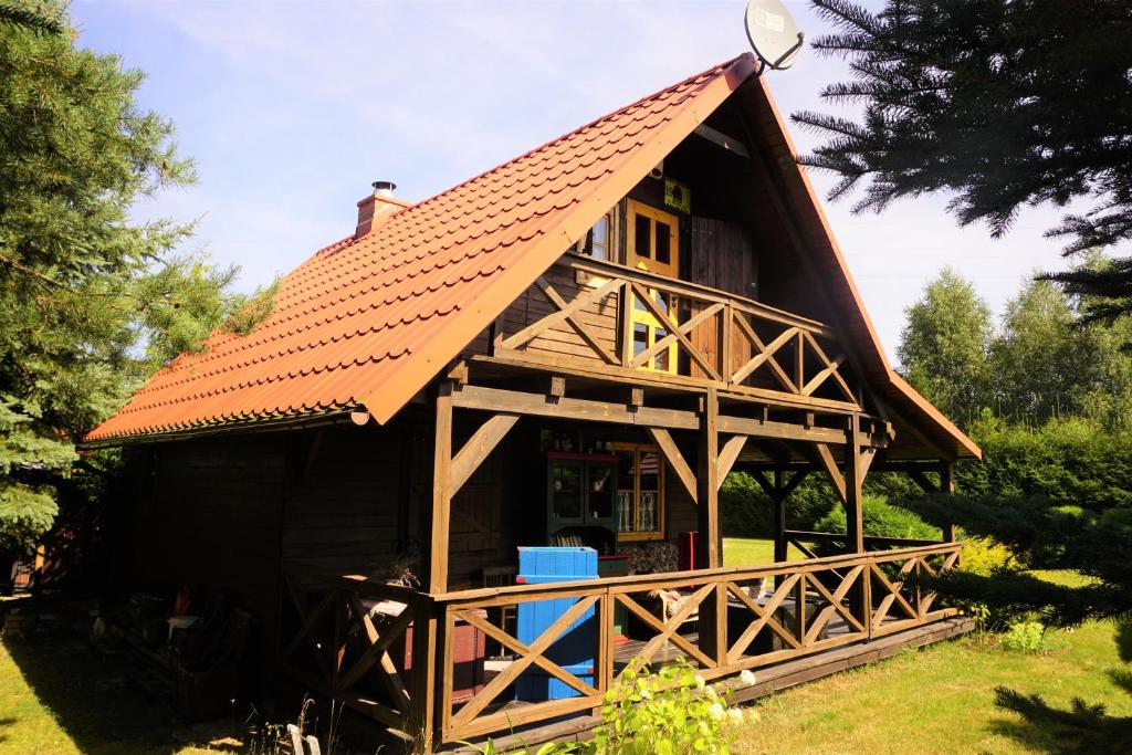 a large wooden house with a red roof at Domek JEZIORACZEK in Urowo