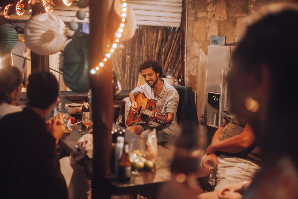 a man playing a guitar in a room with people at João Jungle in Açafora