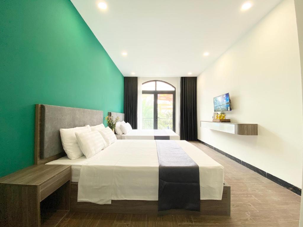 1 dormitorio con 1 cama grande y pared verde en Elpis Hotel Phu Quoc, en Phu Quoc